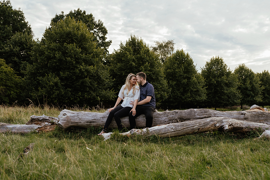 Couple sit on log looking at each other Pishiobury Park Engagement shoot