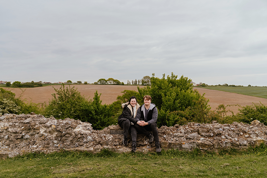 Couple sit together on the castle wall at Hadleigh Castle