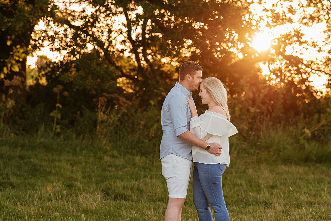 Sunset and couple embracing and he kisses her forehead Hylands Park Engagement Session