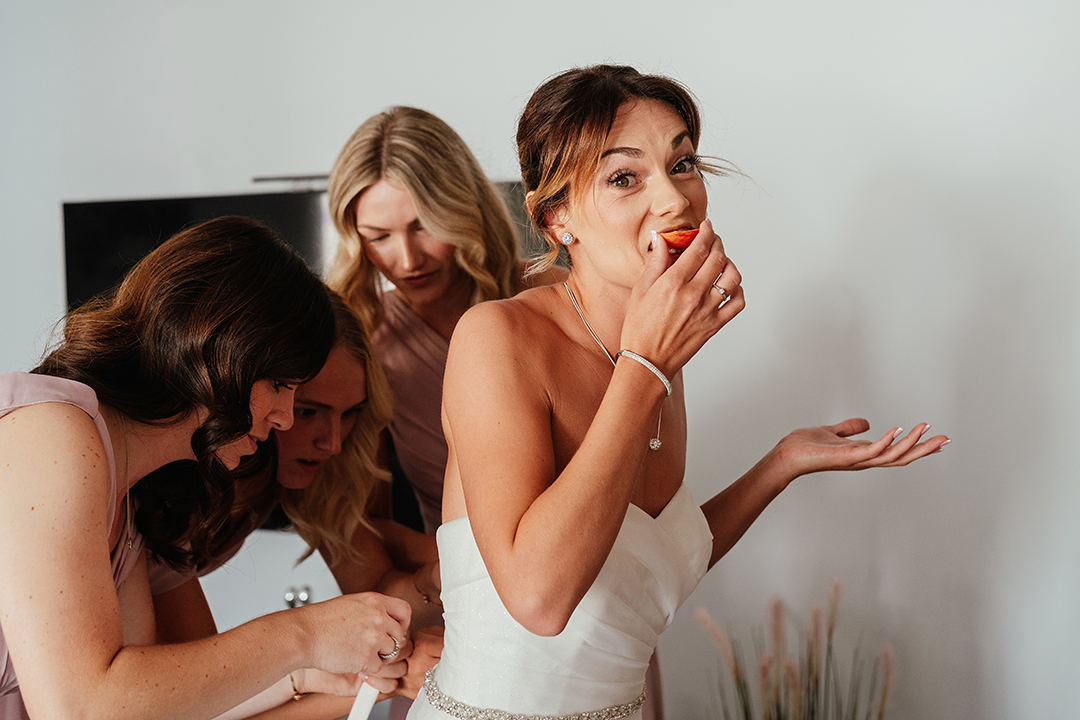 Bride Eats an Apple While Girls do up Dress