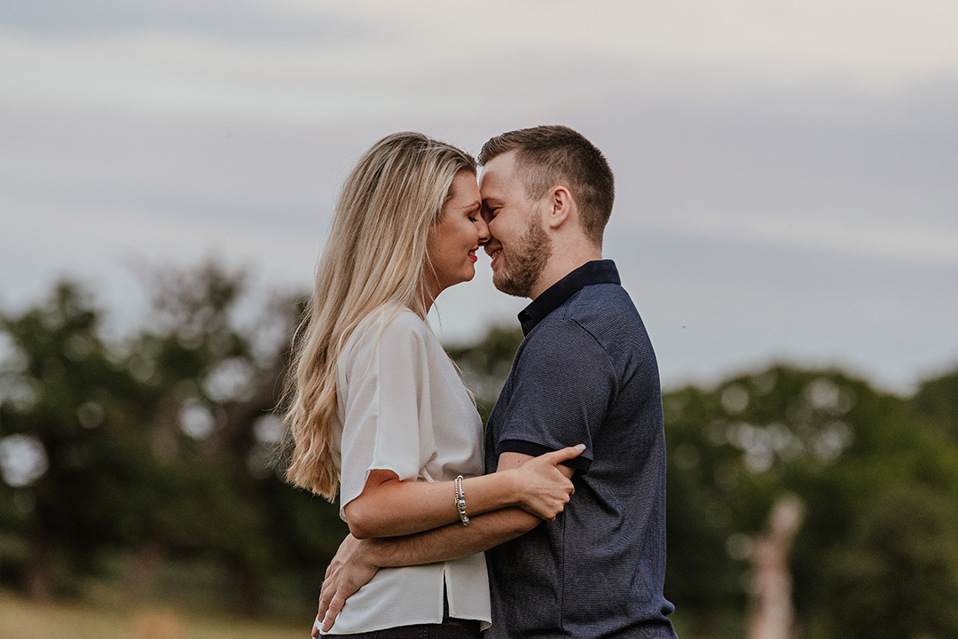 Romantic couple embrace, nearly kissing in Natural sunset Engagement session
