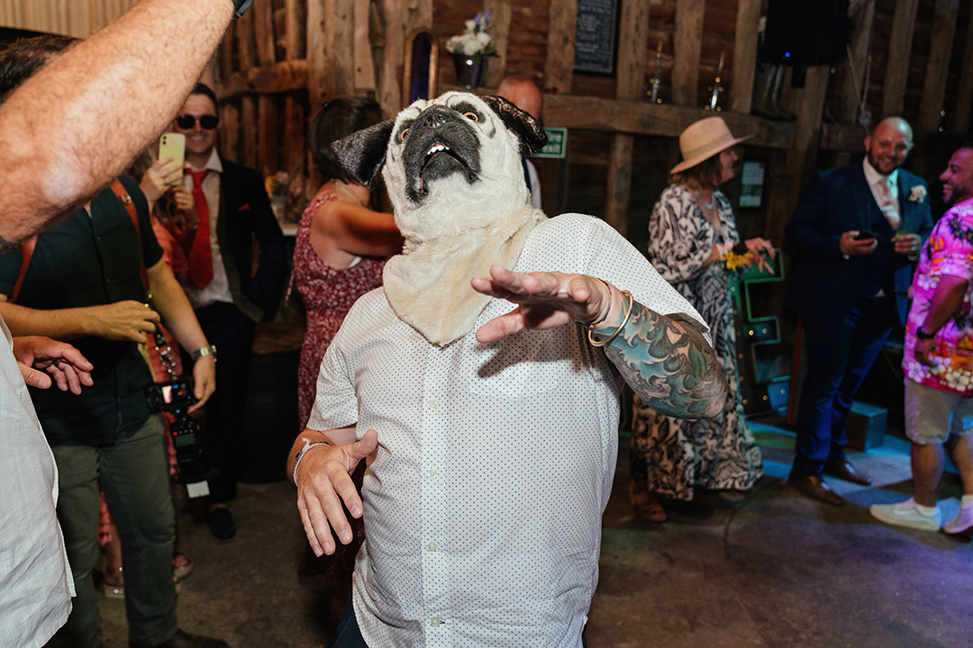 Man in pug mask dancing at Stock Street Farm Barn Wedding