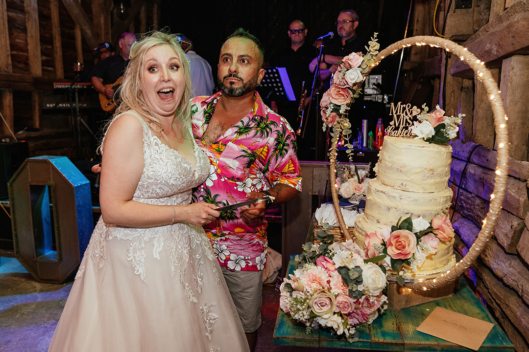 Bride and Groom in a Hawaiian Shirt Cut Wedding Cake at Stock Street Farm Barn Wedding