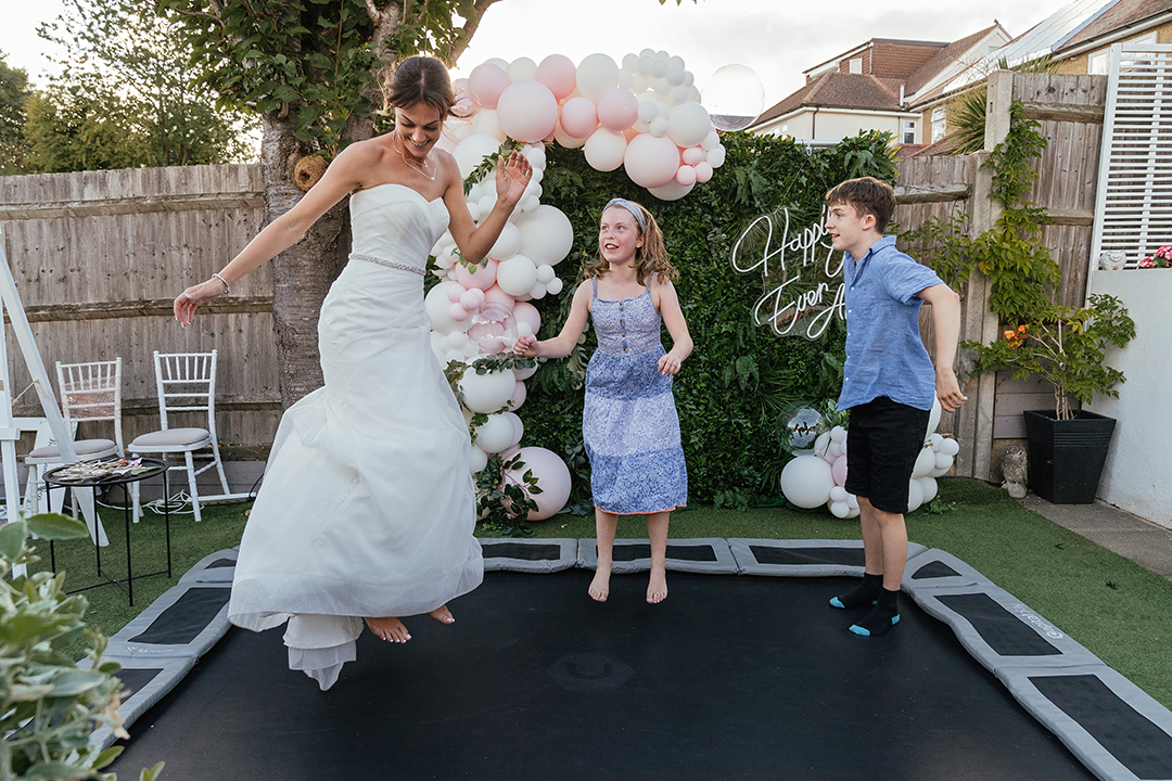 Bride on Trampoline jumping mid air with two kids