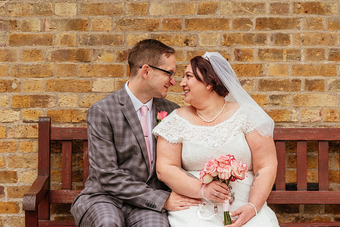 Couple sit on bench with brick wall in background Moot House Wedding Photography Couples Photos