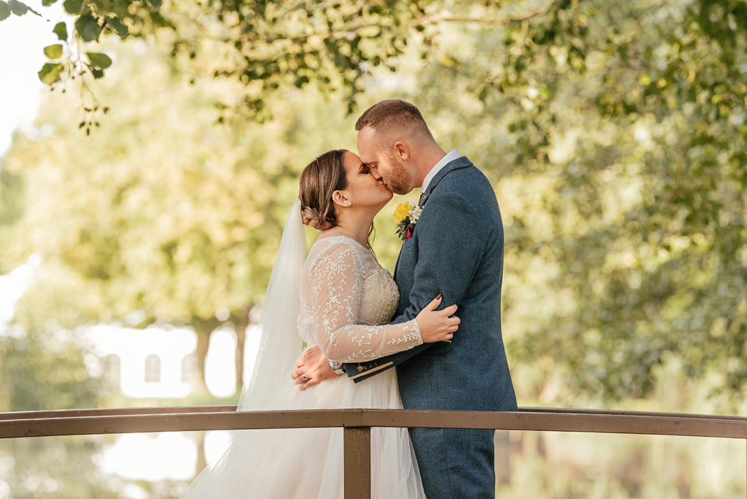 Couple kiss on bench over river Minstrel Court Wedding photography
