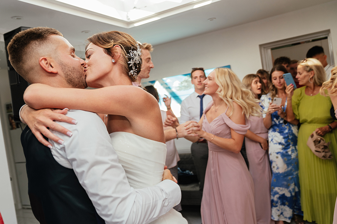 Couple Kiss While Guests Party in the Background
