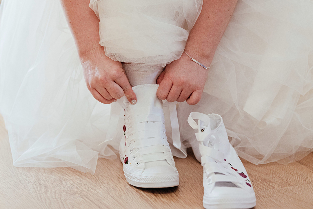 Bride puts on Converse wedding shoes