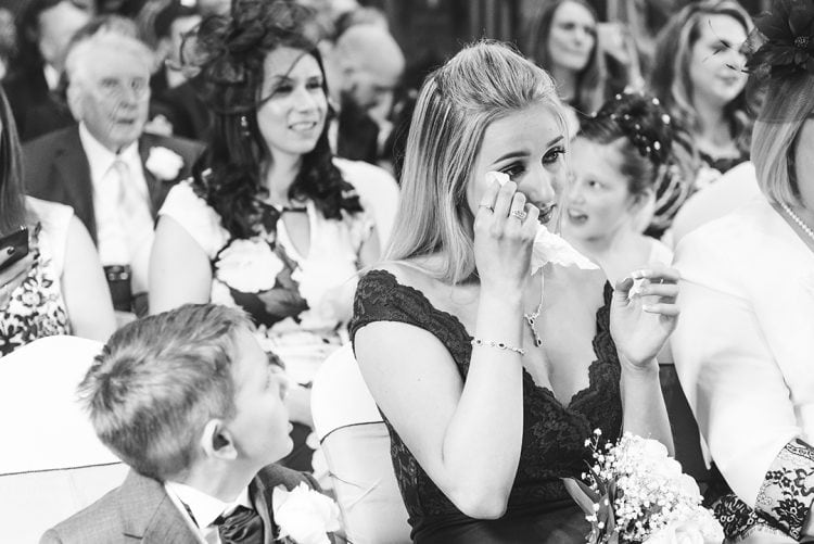 Essex wedding photographer captures Bride's sister wipes tear during emotional wedding ceremony