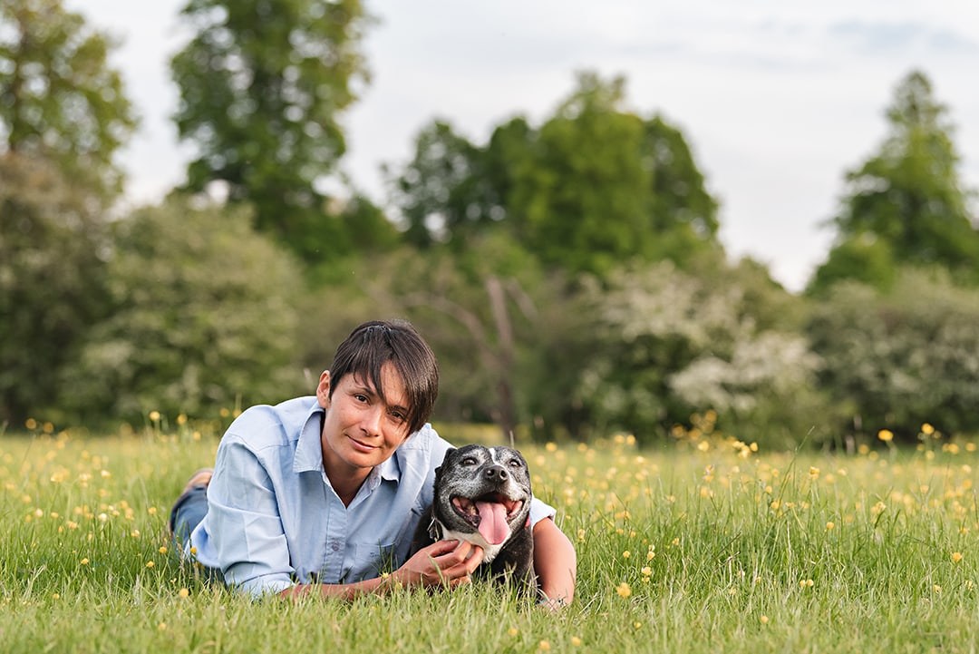 Dog and owner laying in buttercups for photo shoot