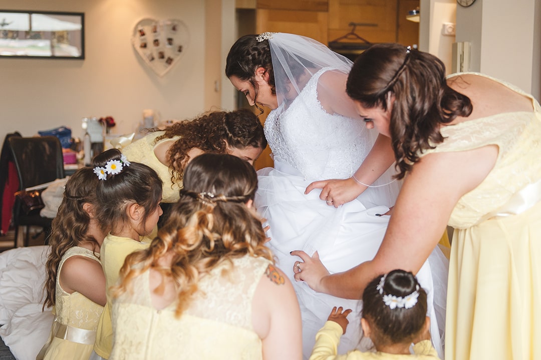 All bridesmaids chip in the help the bride with her dress