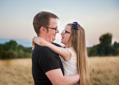 Father and daughter look at each other smiling at sunset photo shoot