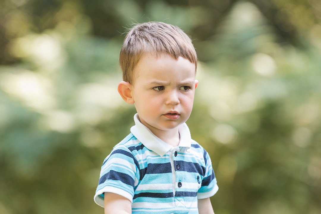 Funny moment of boy frowning in natural photo shoot