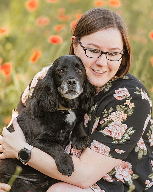 Essex wedding photographer Lindsey at LNZPHOTO cuddling her rescue Dog in Poppy Field