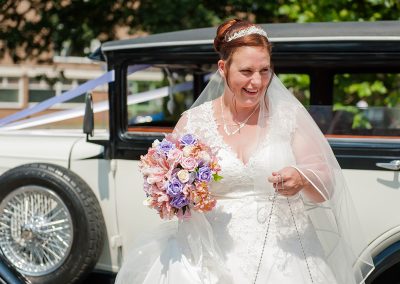 Smiling bride gets out of wedding car at the Moot House
