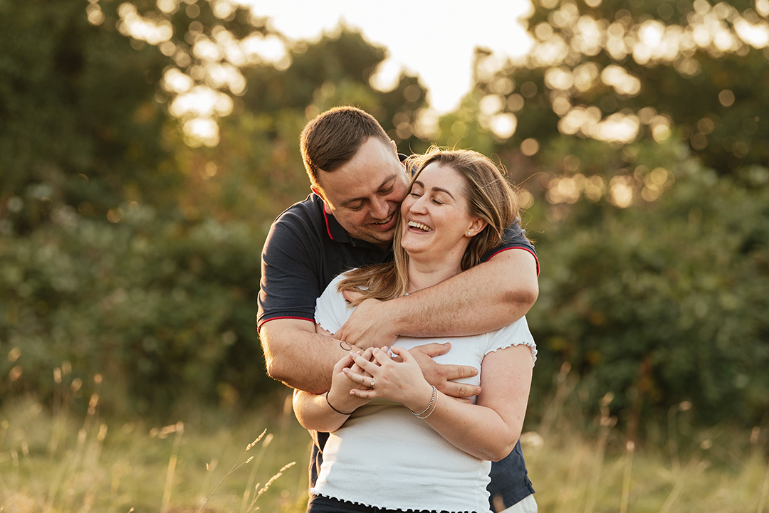 He hugs her from behind making her laugh with sunset in the background Pishiobury Park Pre Wedding Shoot Photos