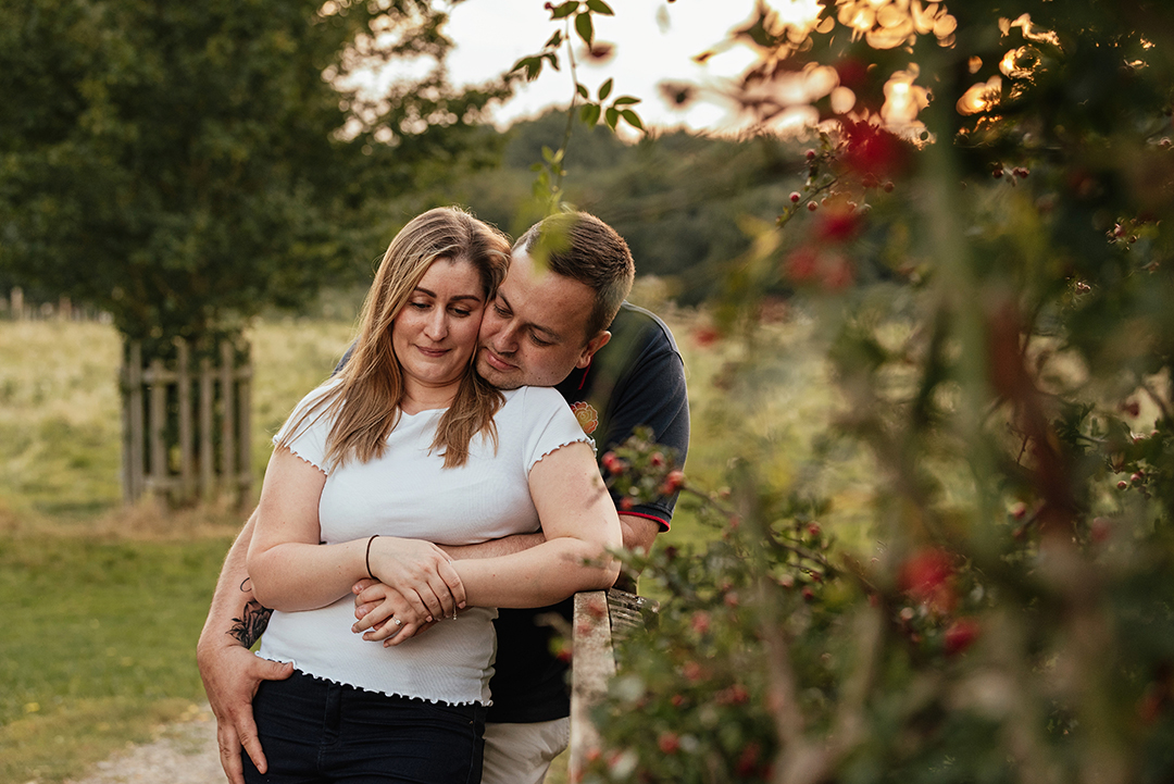 Berrie bush in the foreground and him hugging her from behind in Pre Wedding Shoot Pishiobury Park Sunset