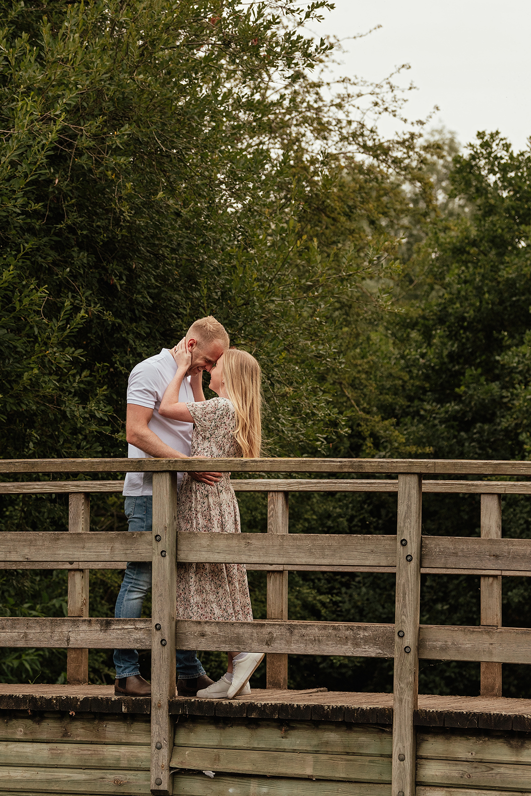 Full length image of Bride pulls groom in for intimate moment on bridge in Natural Pre Wedding Photoshoot at Stanborough Lake