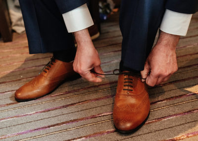 Groom laces up shoes, getting ready