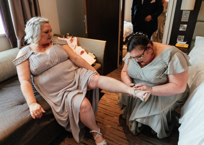 Bridesmaids helping each other with shoes