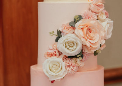 Close up of peach and white flowers on wedding cake