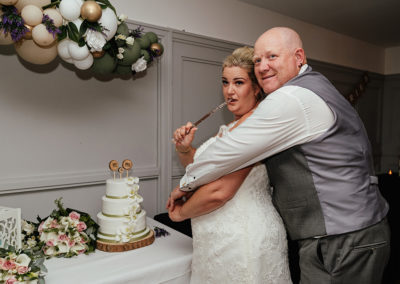 Bride pretends to hold knife to groom before cutting the cake