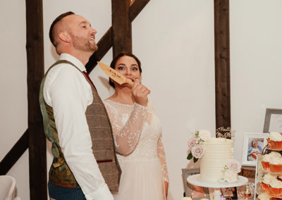 Bride pretends to hold knife to grooms throat before cutting the cake, knife is personalised with their details