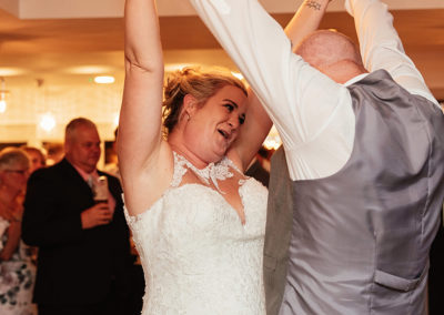 Bride and groom both hold hands in the air together and dance