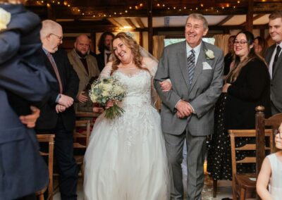 Bride and dad laugh while walking down the aisle