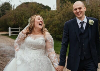 Bride laughing with groom walking along The Reid Rooms