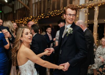 Couple hold hands and dance in barn wedding venue