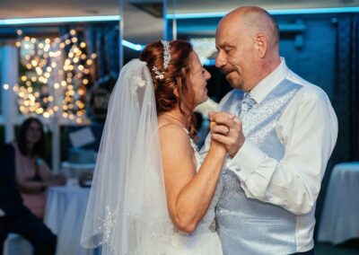 Couple share their first dance holding hands and looking at each other