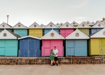 Couple stood in front of beach huts engagement photos