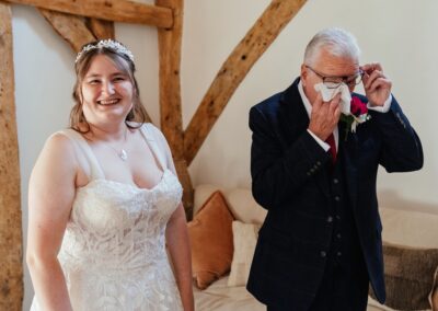 Dad wiping tears while bride smiles