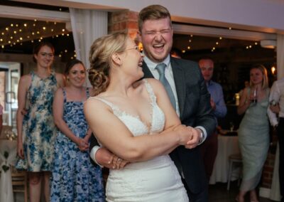 Groom twirls bride on dancefloor as both laugh and have fun